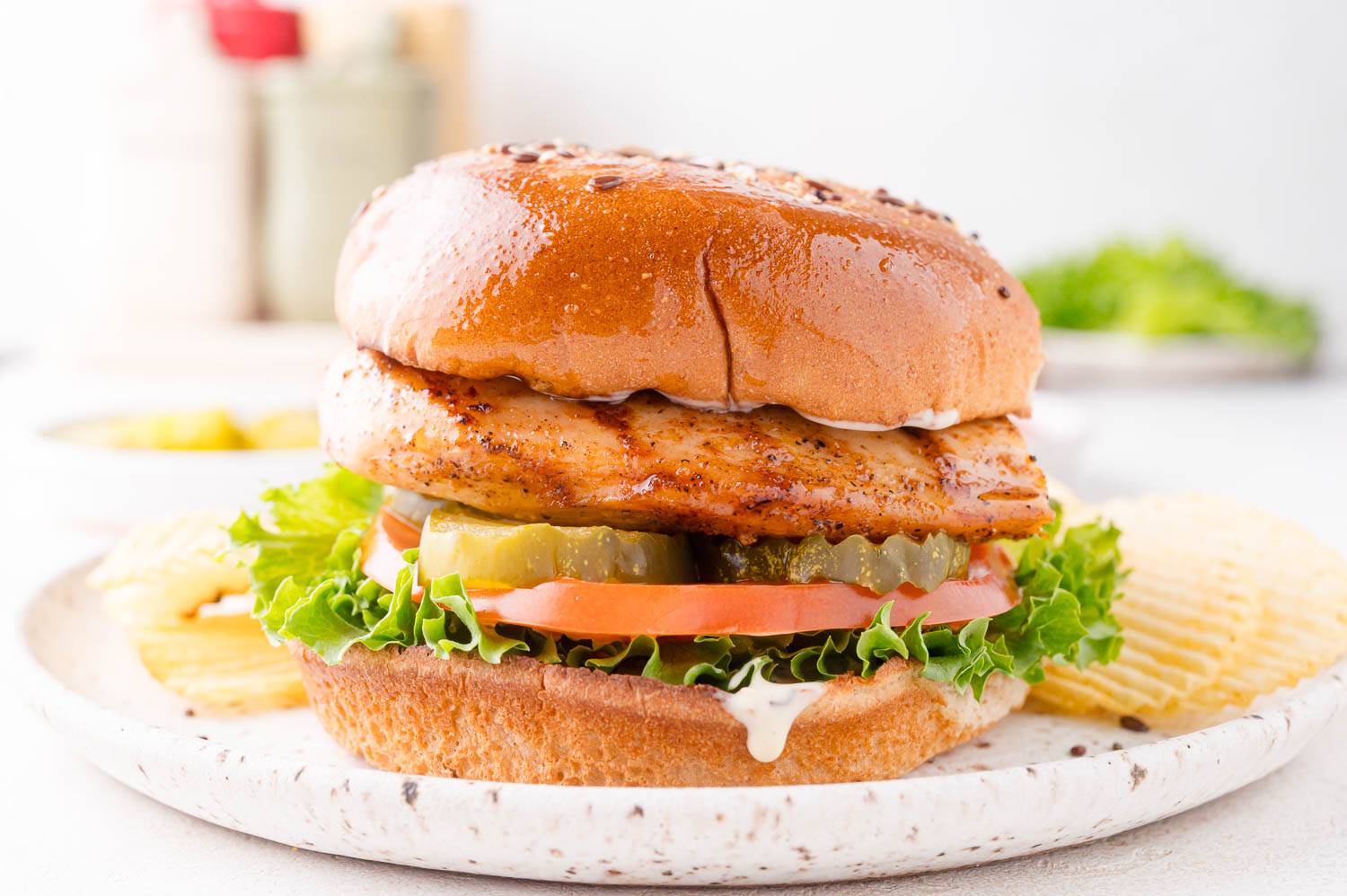 Grilled chicken sandwich on a toasted bun with lettuce, tomato, pickle.