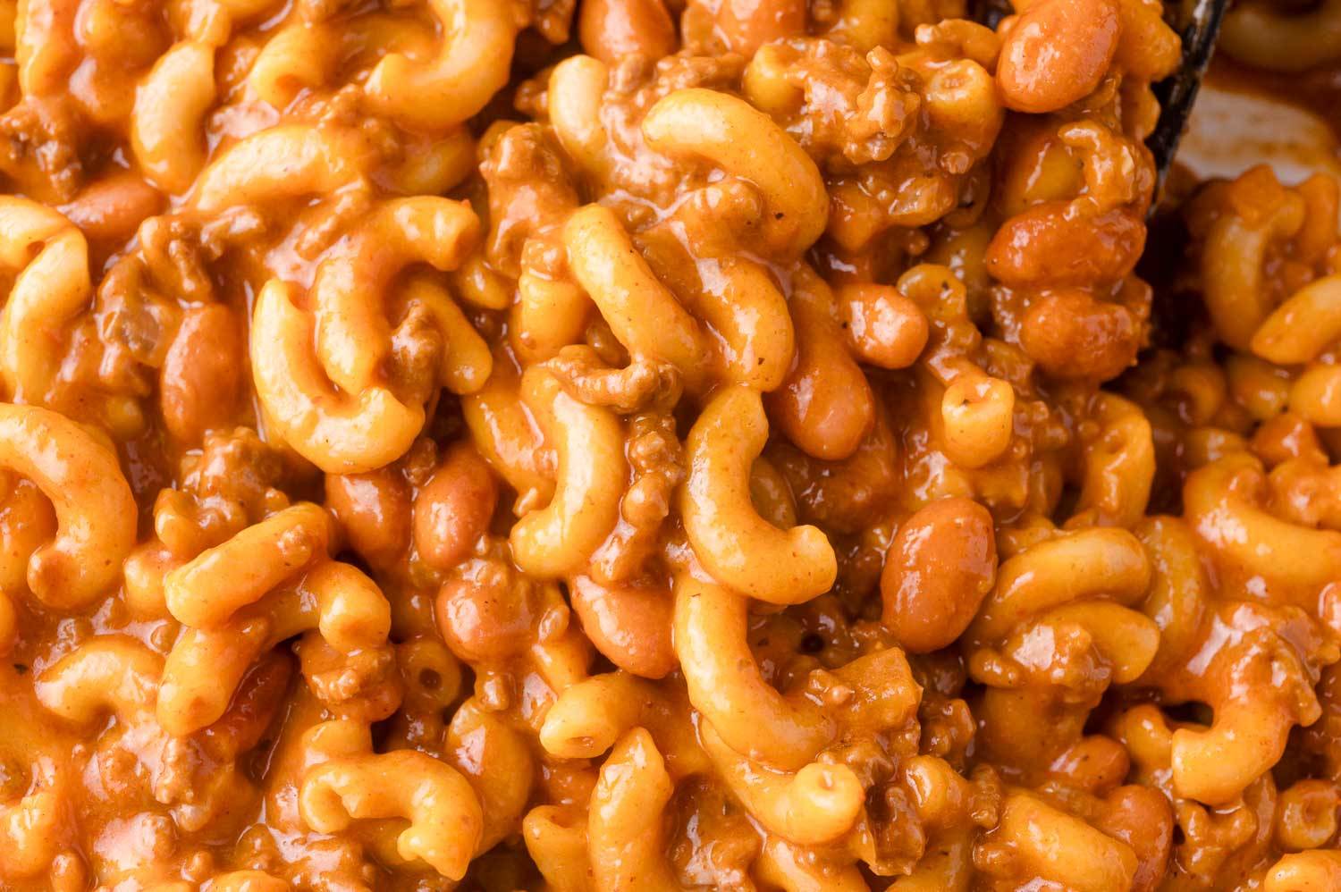 Close up of chili mac, with macaroni noodles and pinto beans in a creamy tomato sauce.