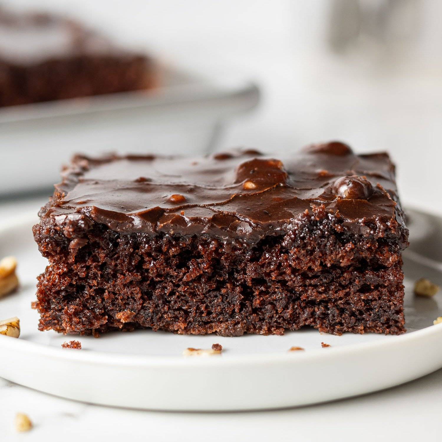 Slice of dark chocolate Texas sheet cake on a white plate.