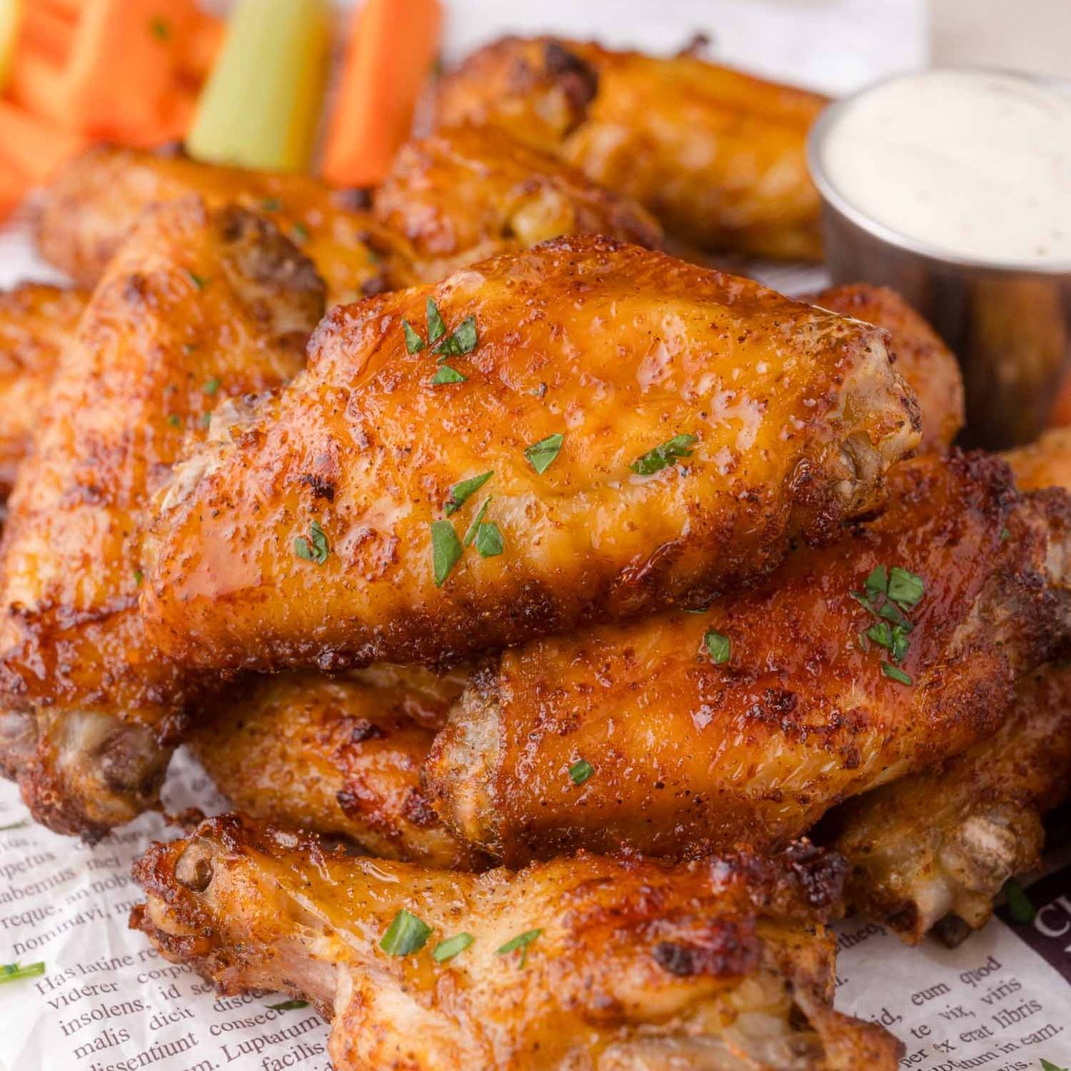 Air fryer chicken wings with ranch, carrots, and celery in the background.