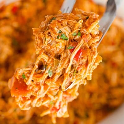 Shredded salsa chicken held between tongs.