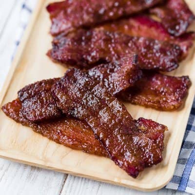 Candied bacon on wooden tray.