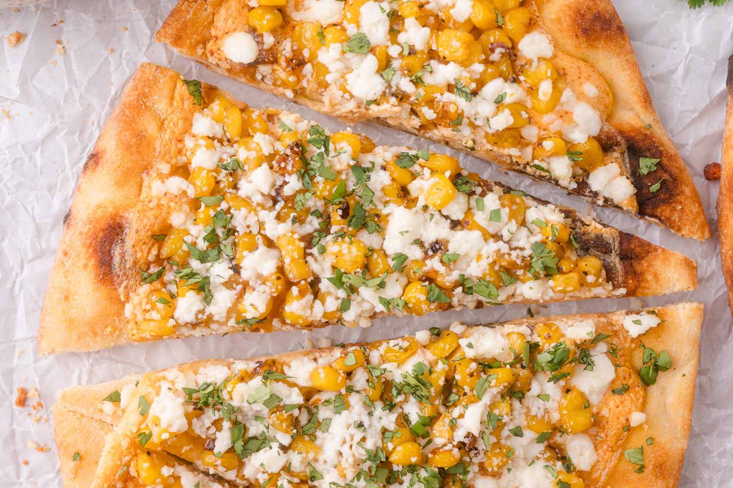 Elote flatbread with corn, cotija cheese, cut into triangles.