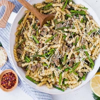 Overhead view of pasta with sausage, dill, and asparagus