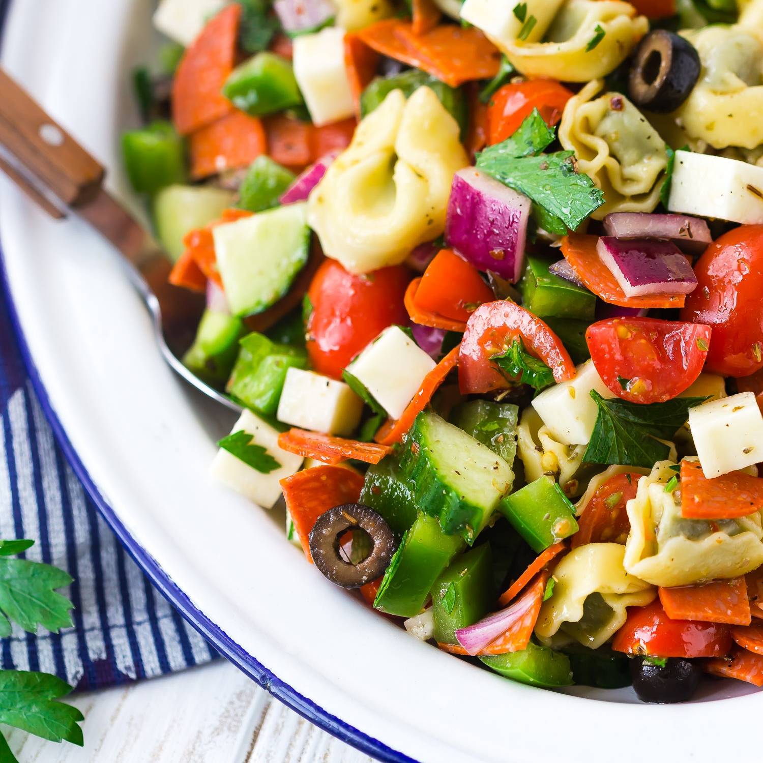 Pasta salad with tortellini, red onions, cucumbers, and more vegetables.