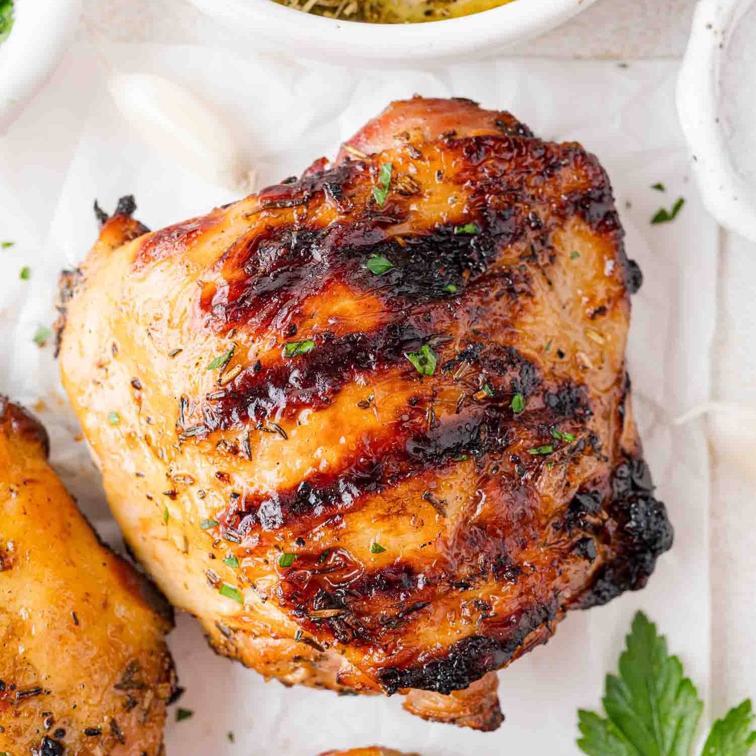 Grilled chicken thigh on a white surface.