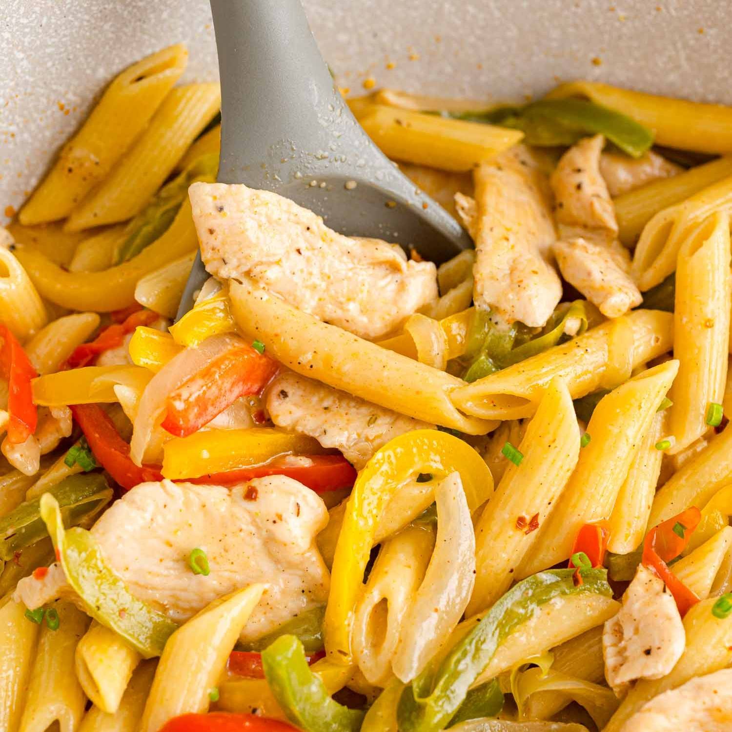 Penne pasta with multi-colored bell peppers, onions, and chicken.