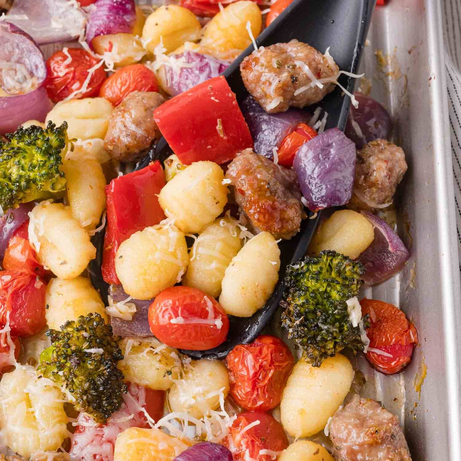 Sheet pan gnocchi with sausage, veggies, and shredded Parmesan cheese.