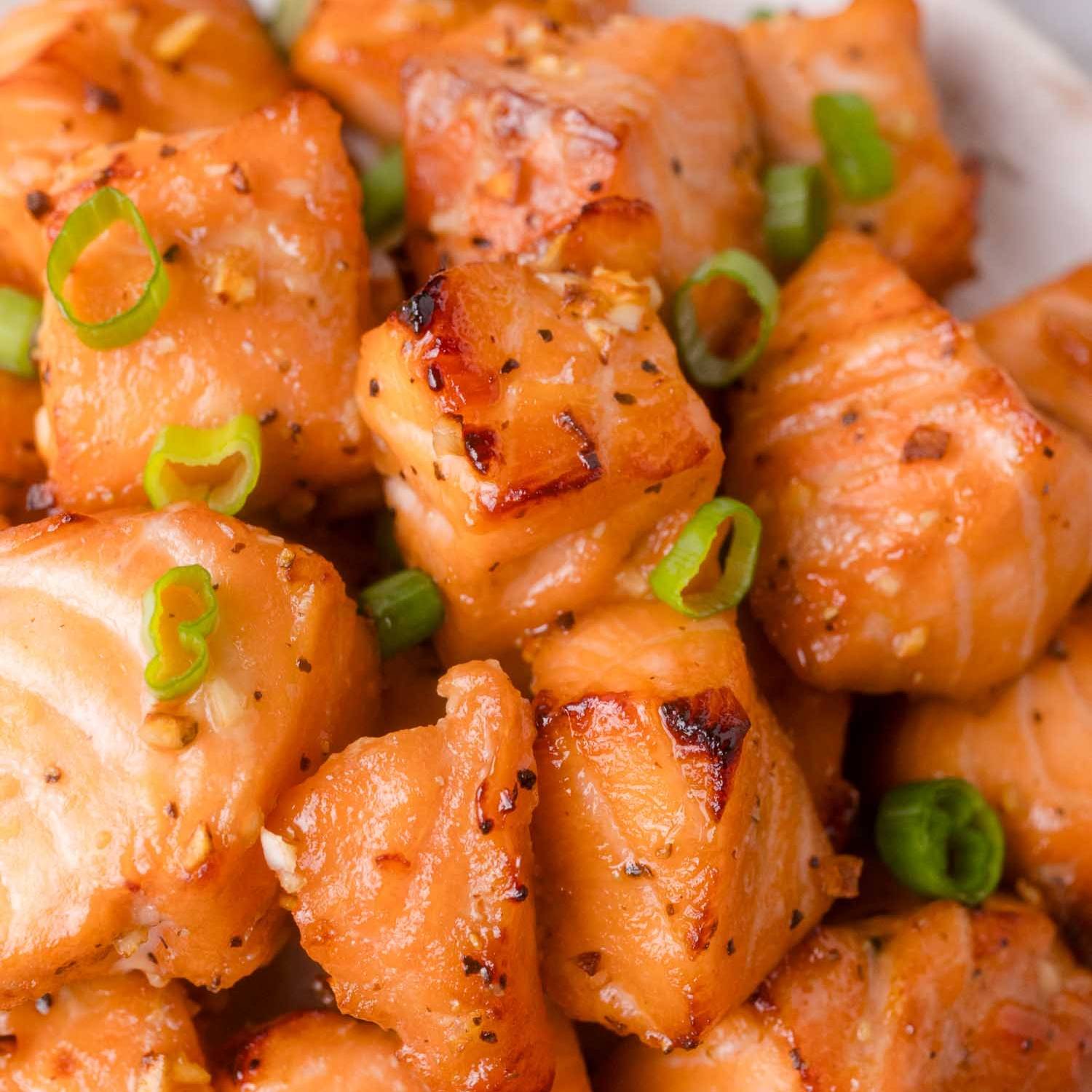 Lightly browned cooked salmon bites, garnished with sliced green onions.