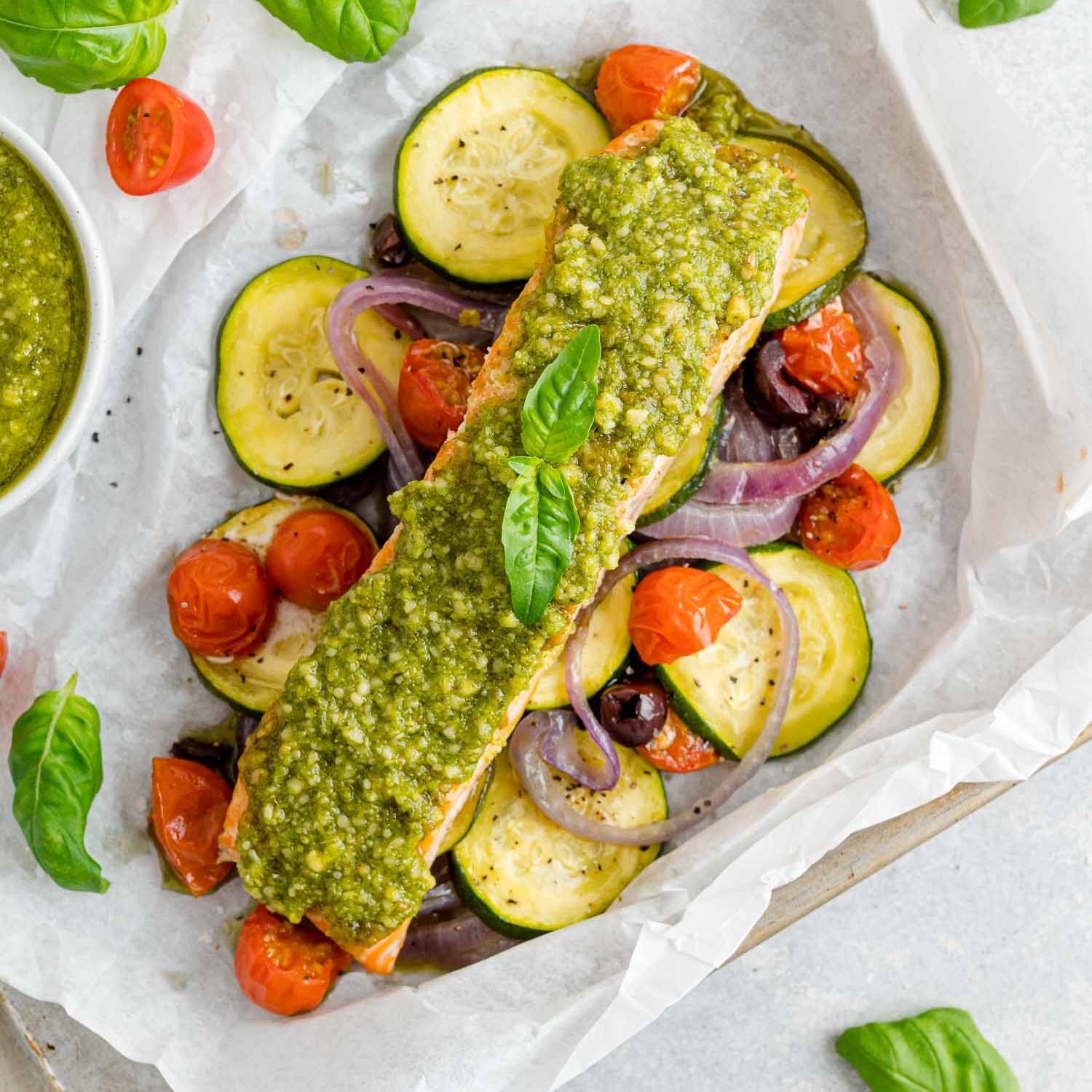 Salmon and vegetables, topped with pesto, wrapped in parchment paper.