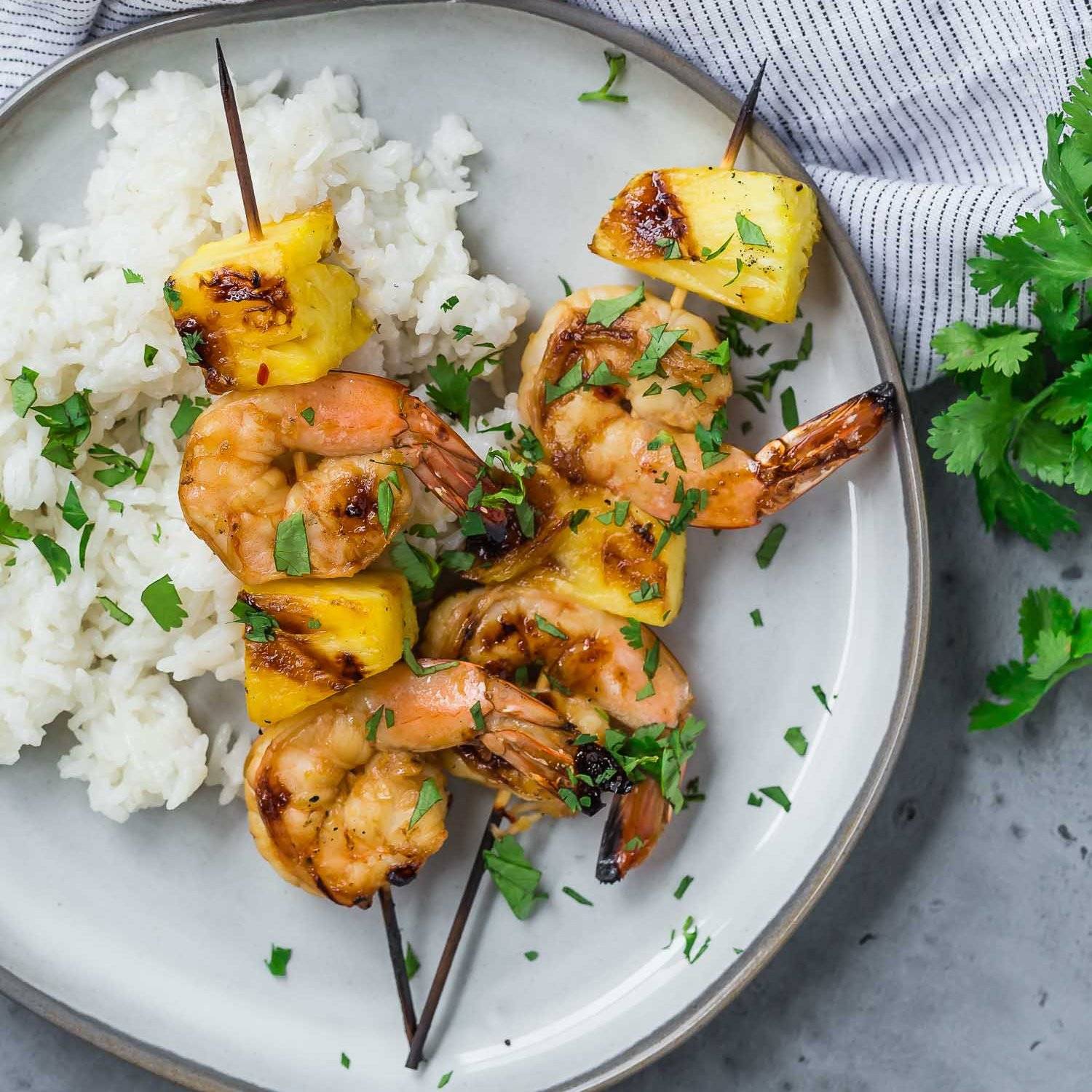 Two shrimp kabobs on a plate with rice.