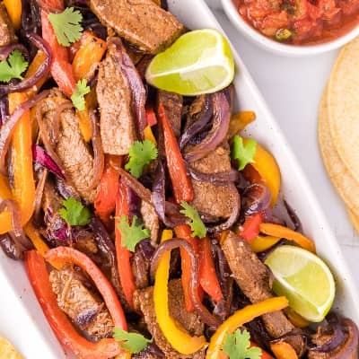 Steak fajitas on a large white platter.