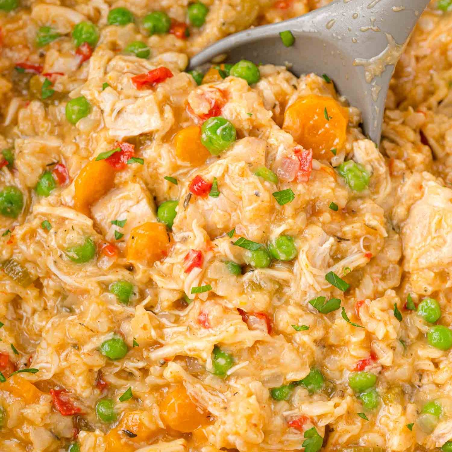 Crockpot chicken and rice with a large grey serving spoon.