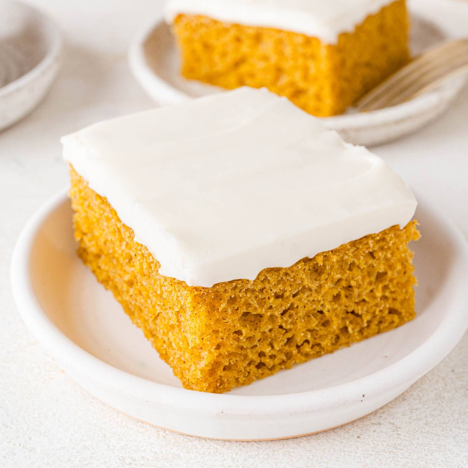 Pumpkin bar with cream cheese frosting on a plate.