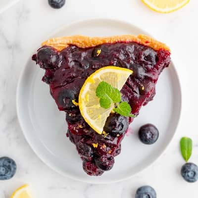Slice of fresh blueberry pie on a white plate.