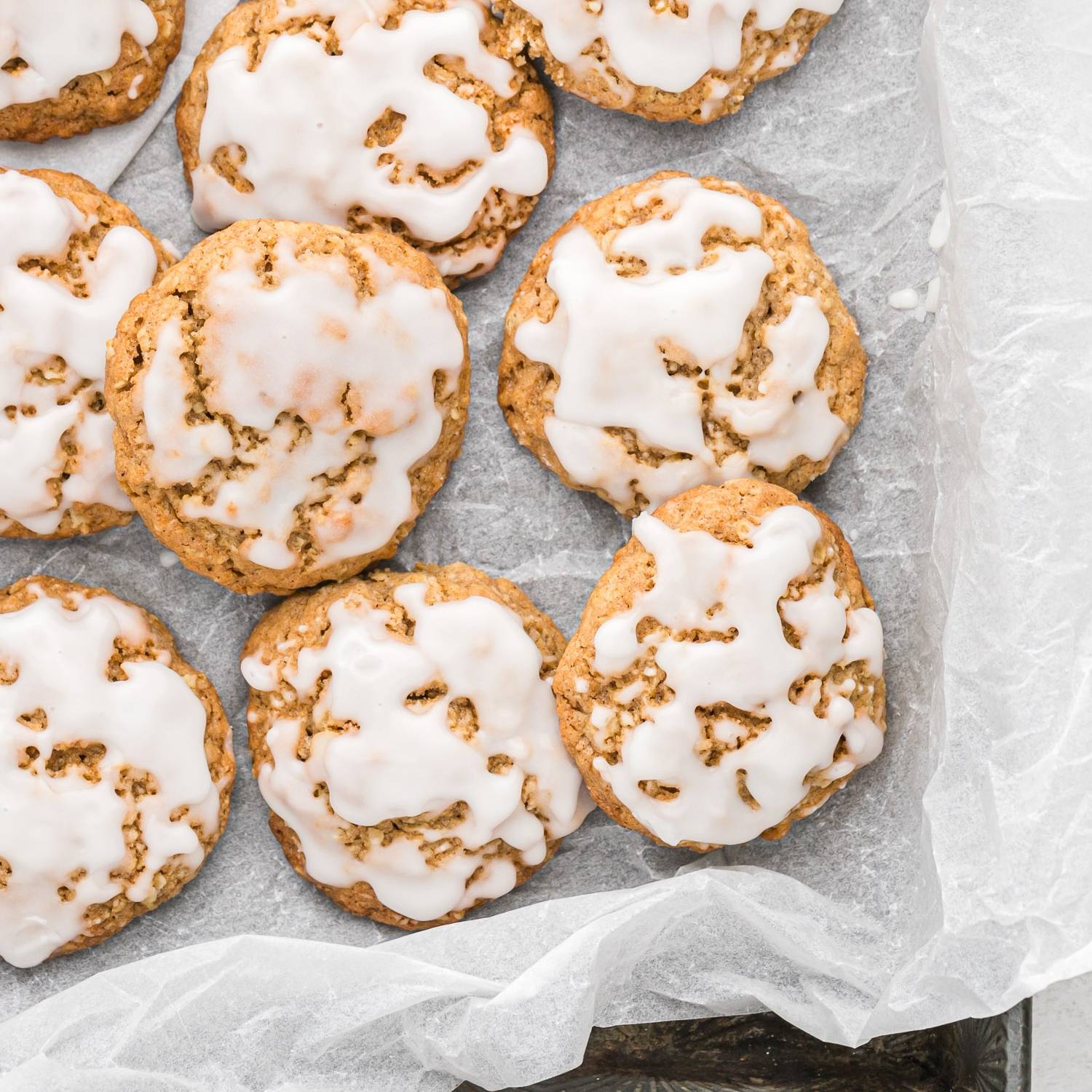 Glazed oatmeal cookies on parchment paper.