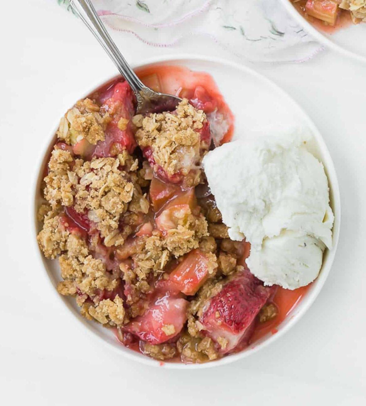 Overhead view of a strawberry rhubarb crisp and ice cream.