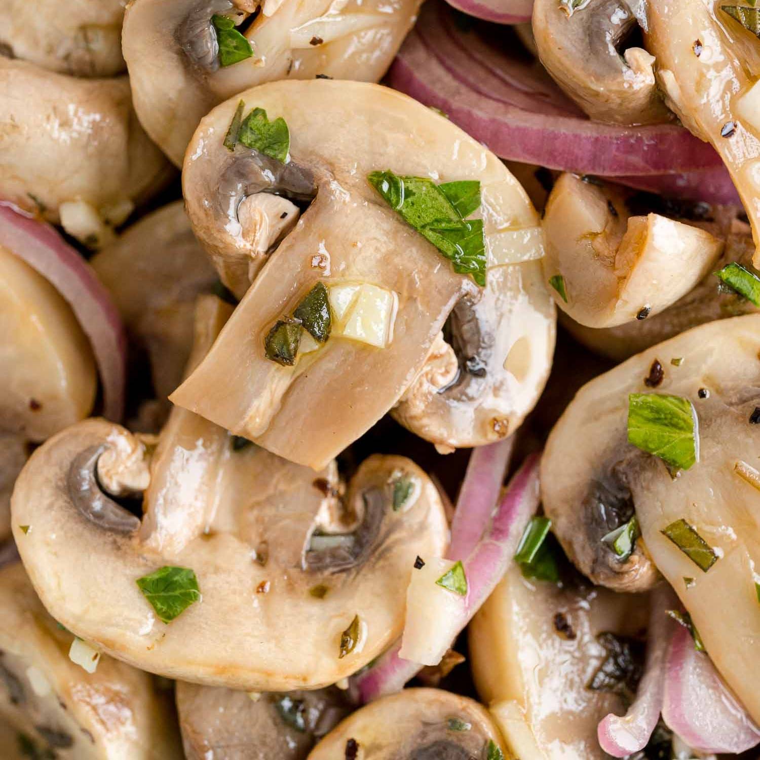 Close up of marinated mushrooms with herbs and shallots.