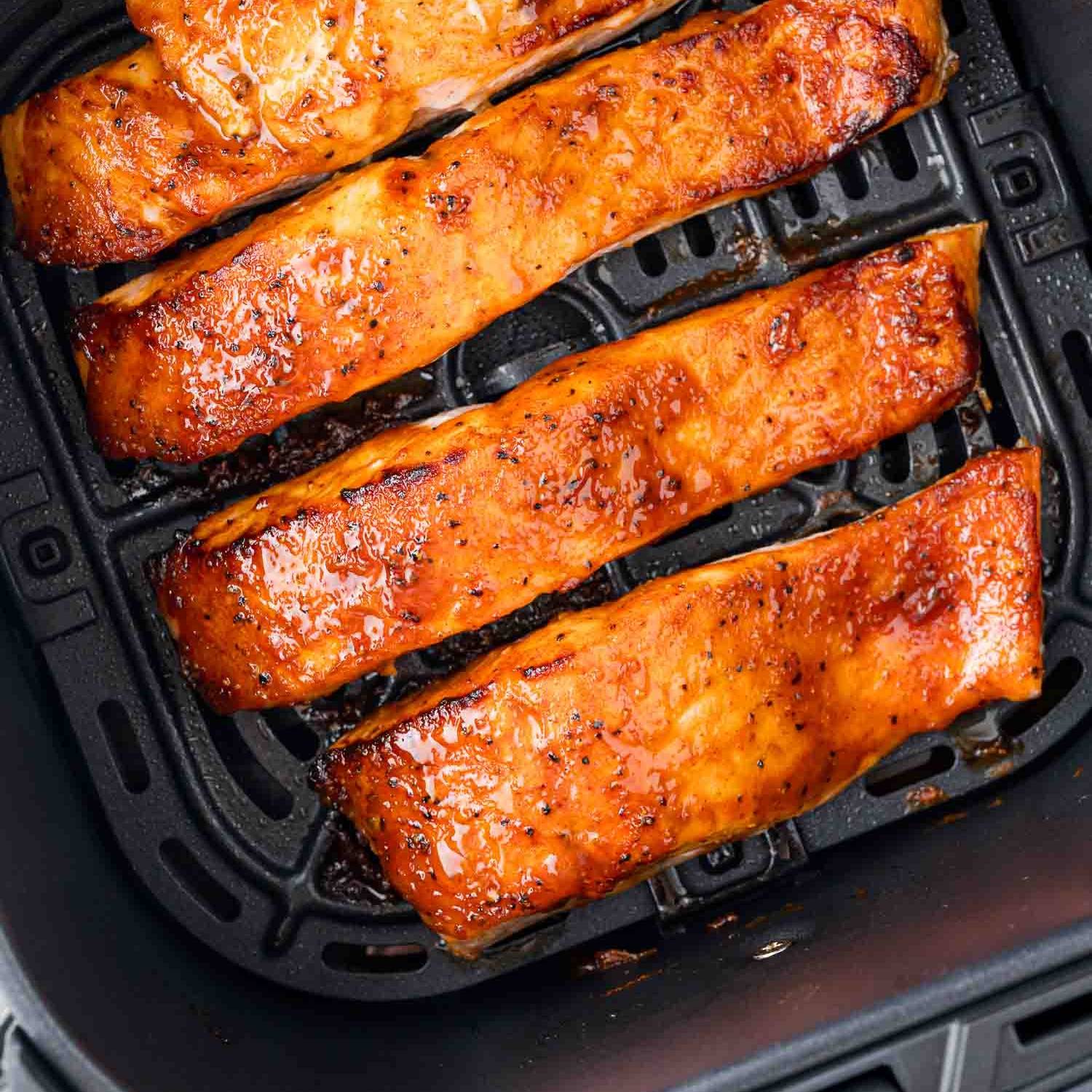 Four fillets of salmon in an air fryer.