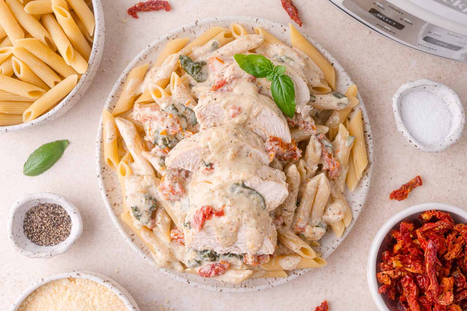 Slow cooker tuscan chicken, sliced and served over cooked penne pasta.