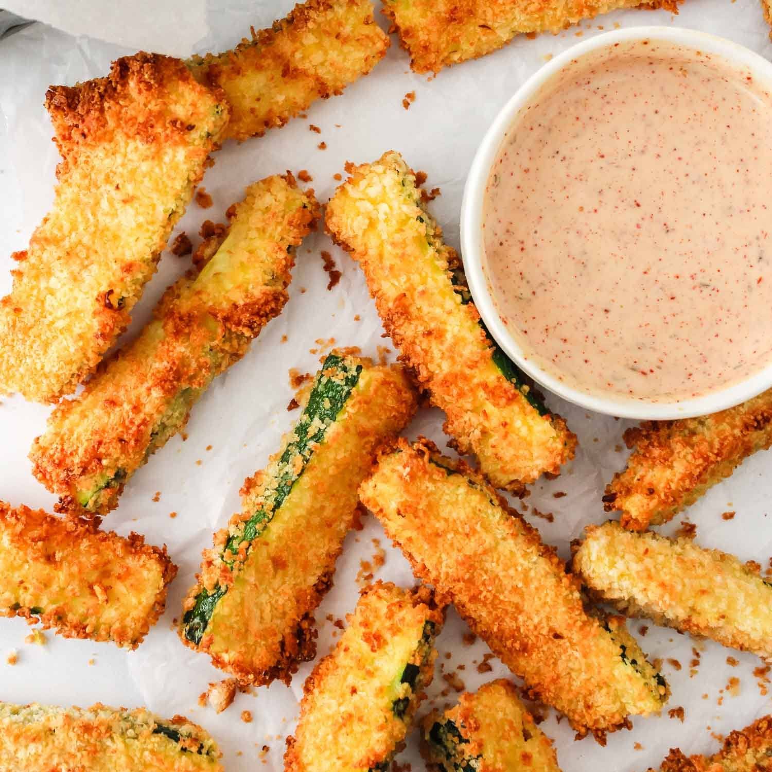 Air fryer zucchini fries with a reddish sauce.