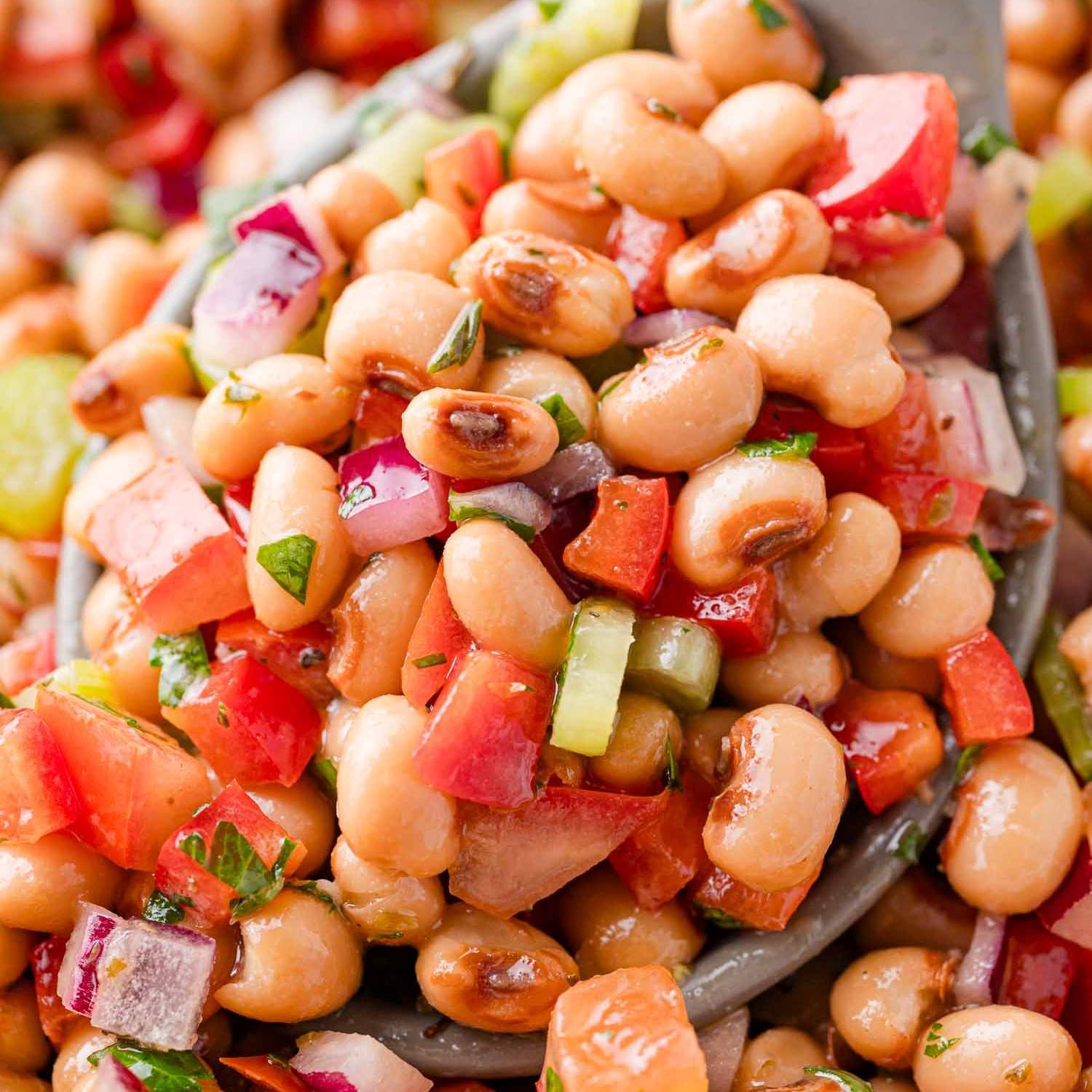 Close up image of salad with black-eyed peas, tomatoes, red bell peppers, celery, and onions.
