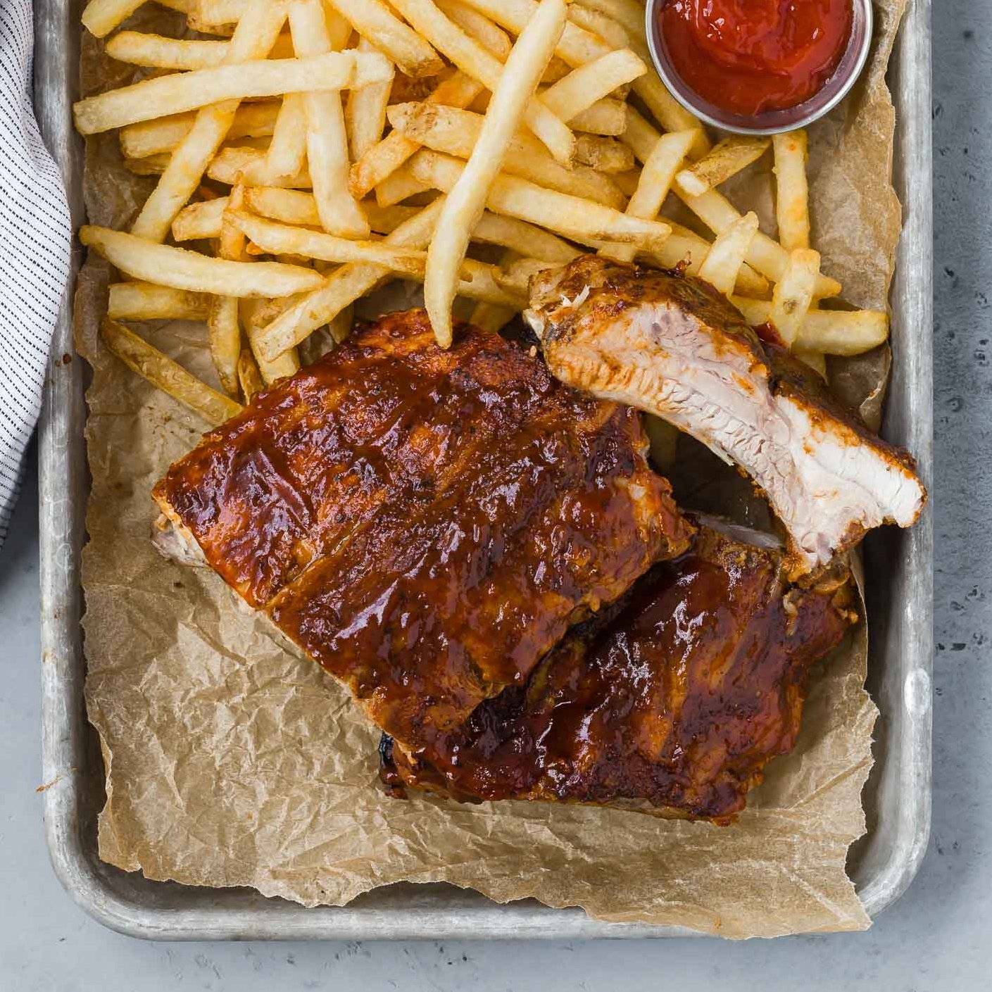 Slow cooker ribs on a pan with french fries.