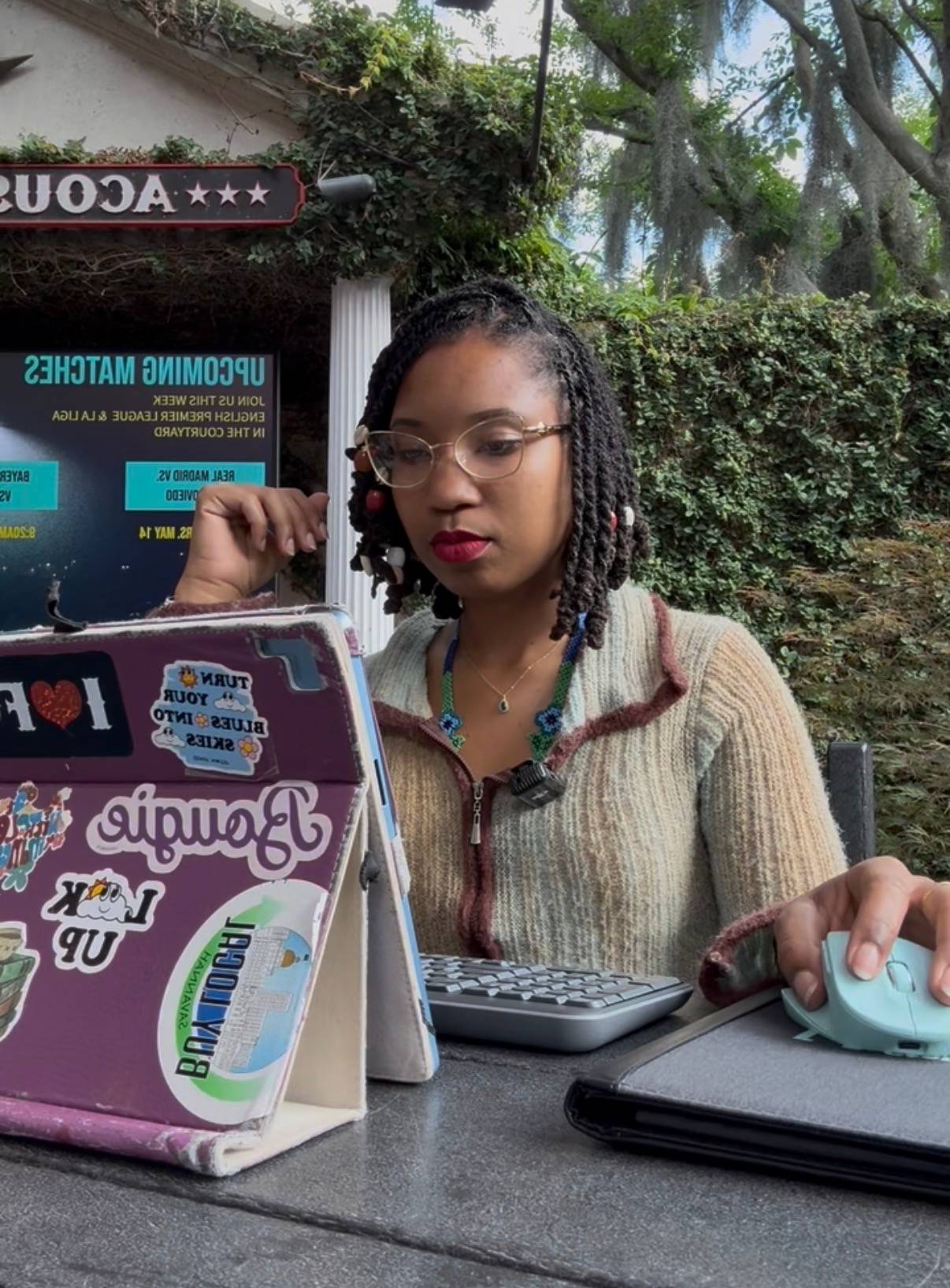 Brandywine sitting in front of her computer that has a purple cover covered in stickers from local businesses.