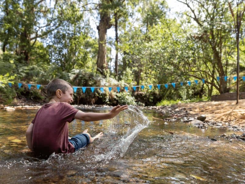 Boy sitting and splashing about in a creek