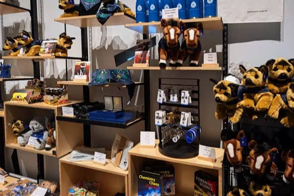 Shelves in a museum gift shop stocked with plush toy police dogs, branded merchandise and books including Chemistry Chaos and Forensic Science.