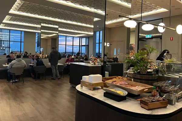Hotel breakfast buffet at Oakwood Premier Melbourne, with guests seated at tables and a spread of pastries and food on the counter.