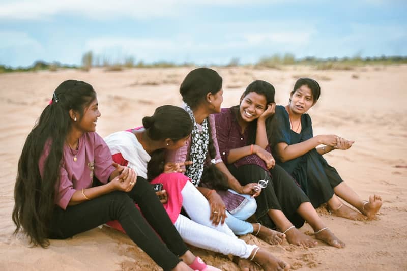 A group of people sitting on top of a sandy beach