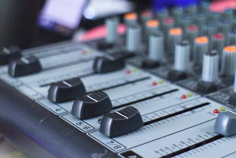 Audio mixing console with black faders and colorful knobs in a studio