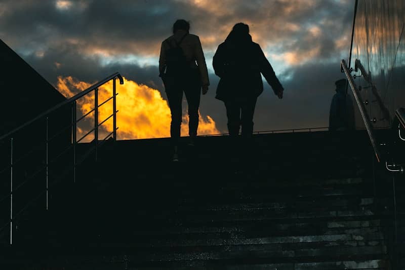 Two people walk up stairs at dusk.