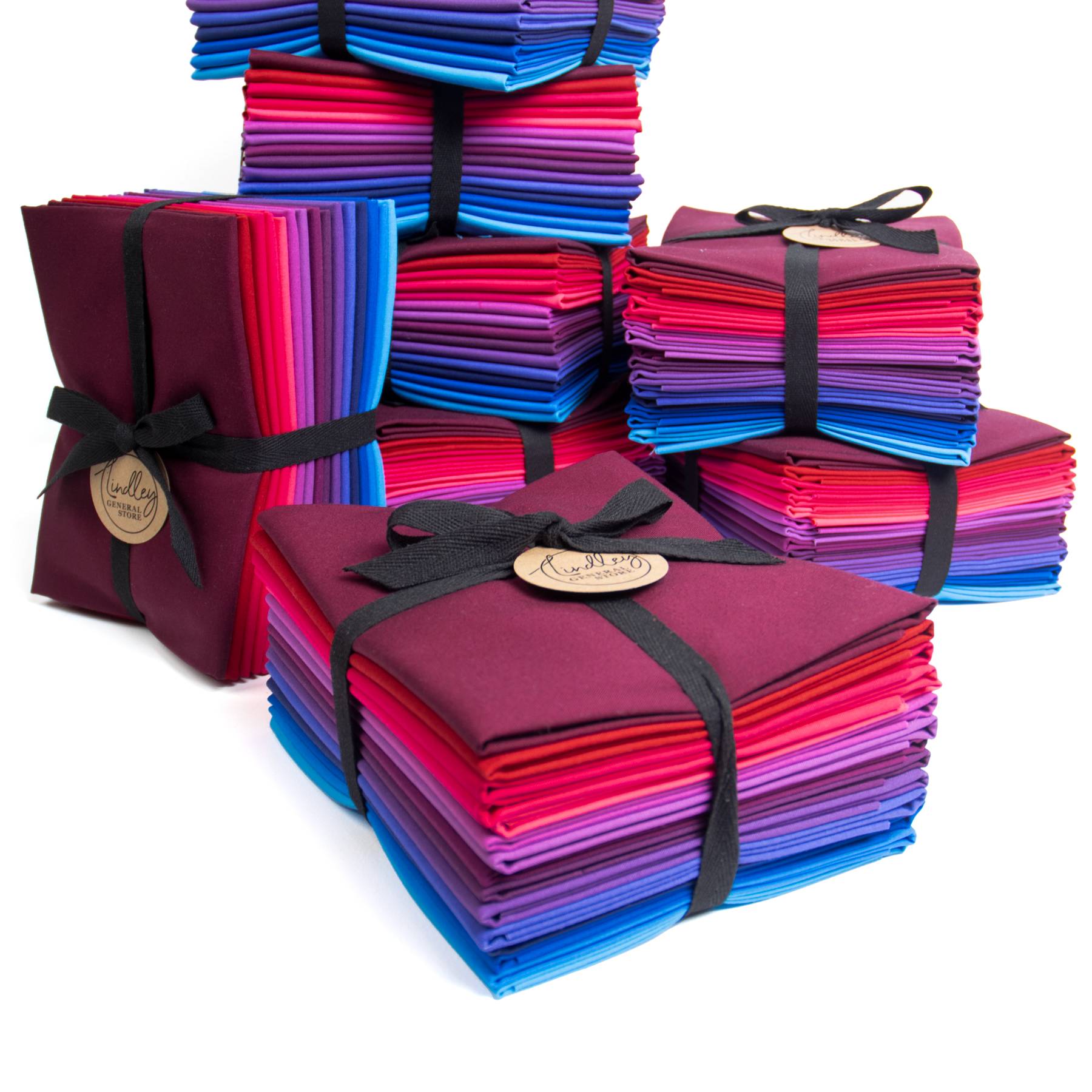 a stack of fat quarter bundles, each featuring shades of purple, pink, blue, and red.