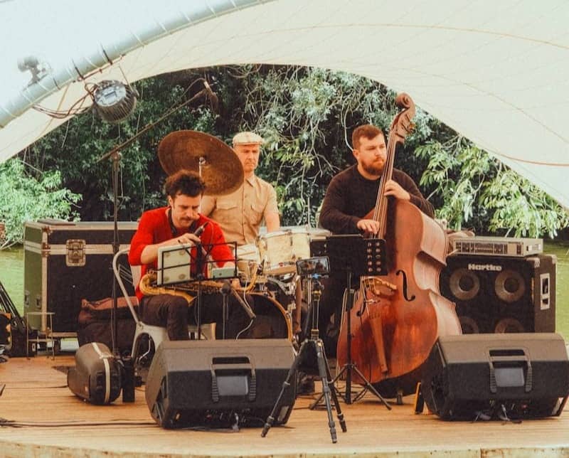 A jazz band performs outdoors under a white canopy.