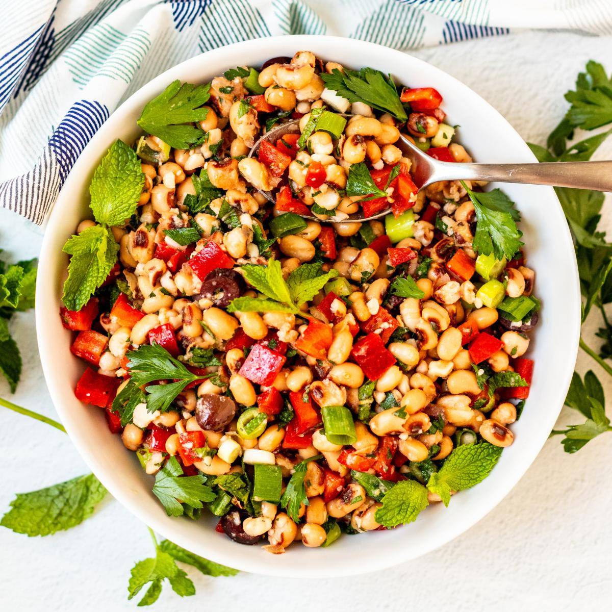 Bowl of black eyed pea salad with fresh herbs and olives.