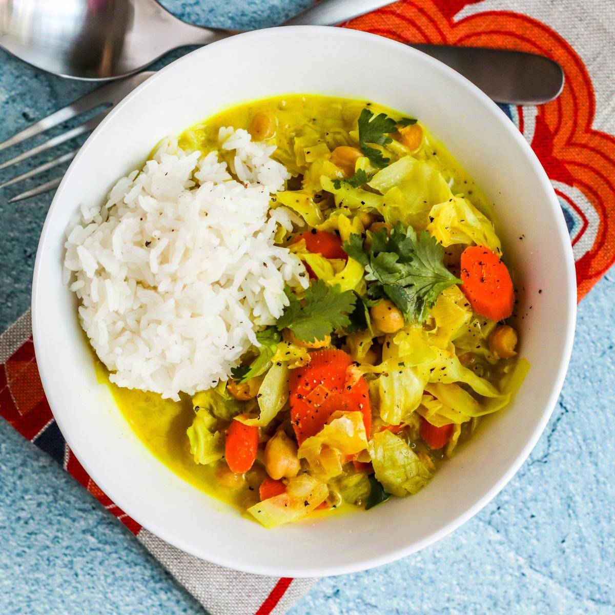 Bowl of cabbage and chickpeas curry with a scoop of rice.