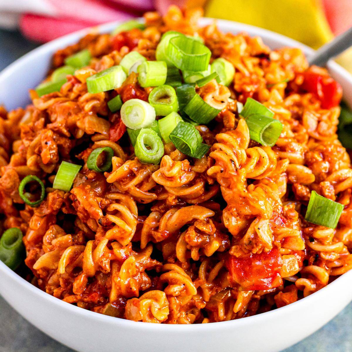 Bowl of vegan taco pasta made with rotini and soy chorizo and topped with green onions.