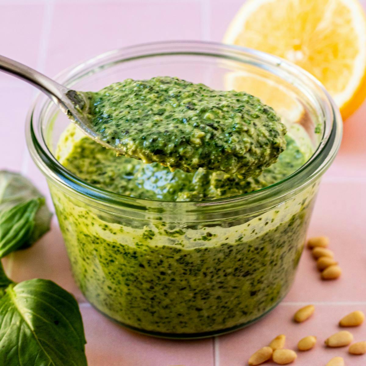 Spoon in a bowl of pesto sauce.