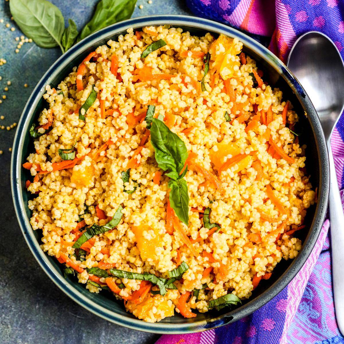 Bowl of Mediterranean millet salad with orange, carrots, and basil.