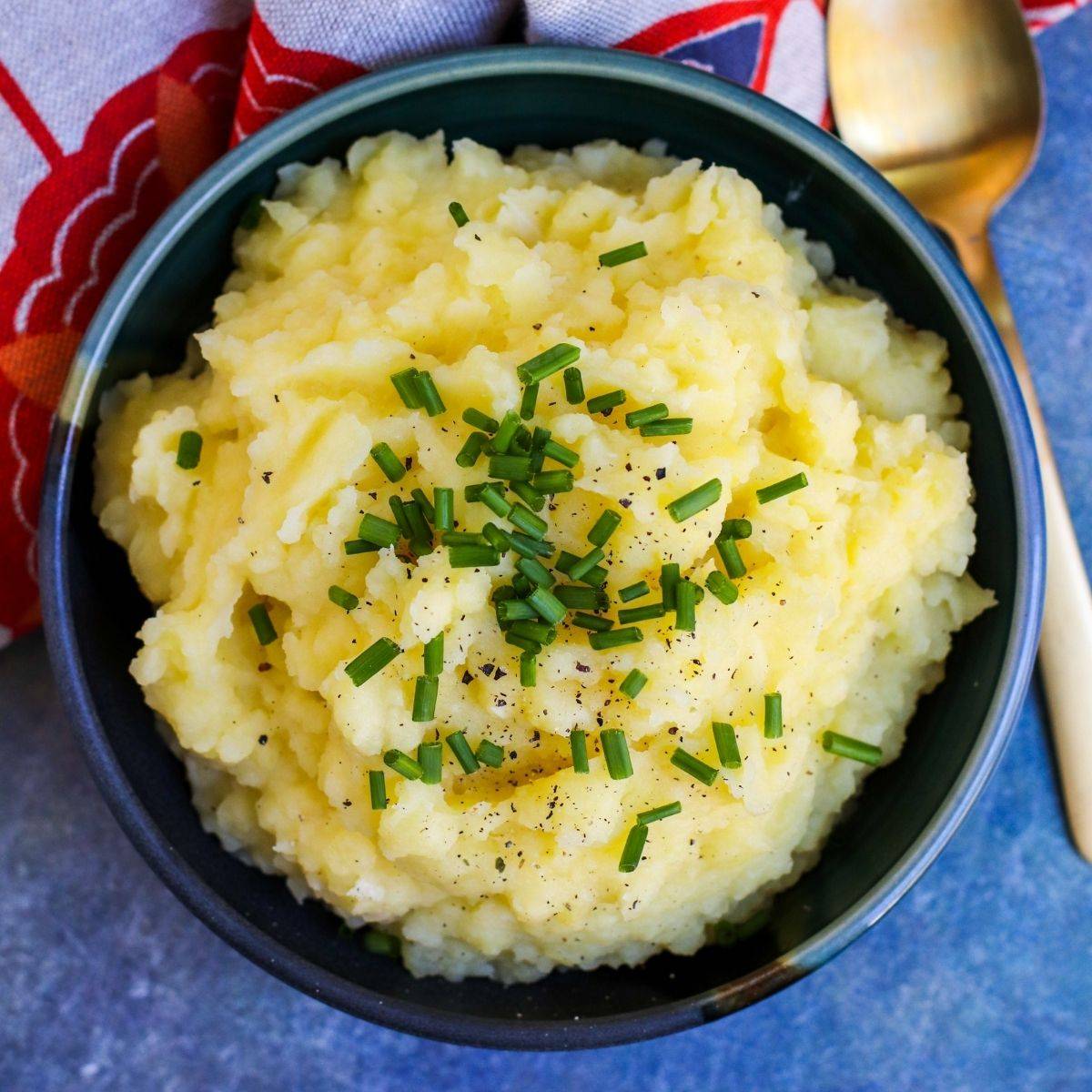 Bowl of olive oil mashed potatoes topped with chives.