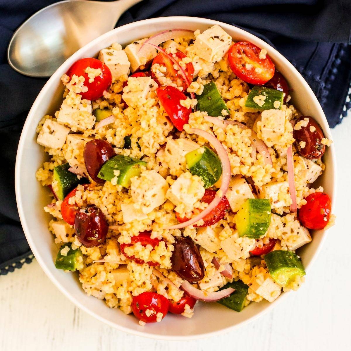 Greek millet salad with tomatoes, cucumbers, red onions, Kalamata olives, and vegan feta cheese.