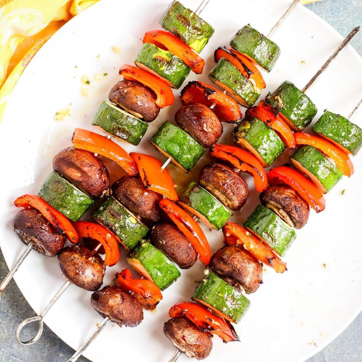 Grilled veggie skewers with mushrooms, zucchini, and red bell peppers.
