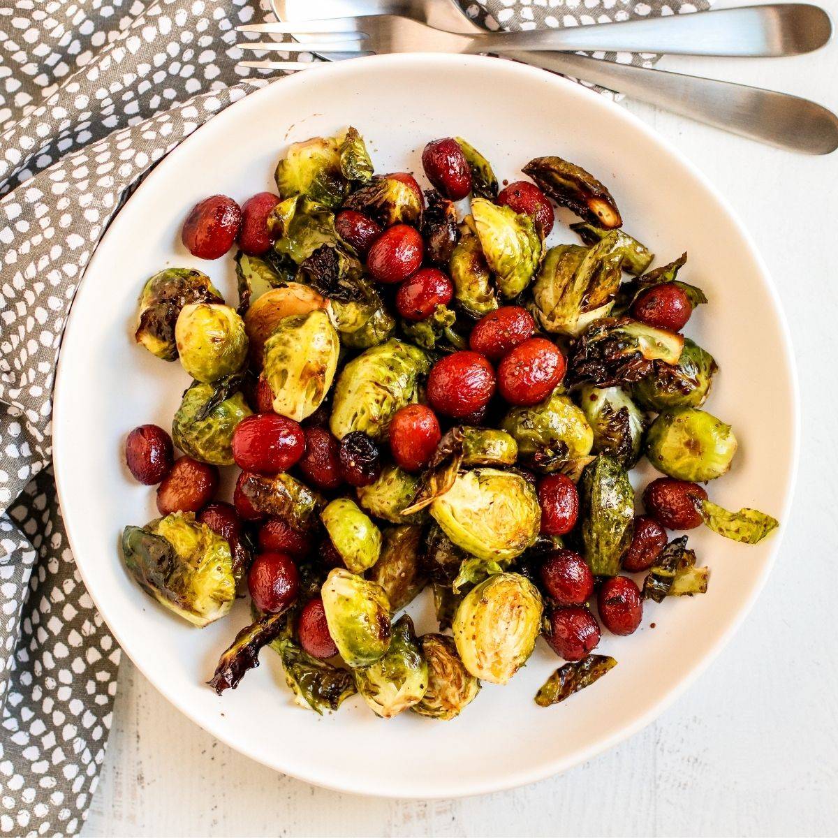 Plate of roasted Brussels sprouts and grapes drizzled with balsamic glaze.
