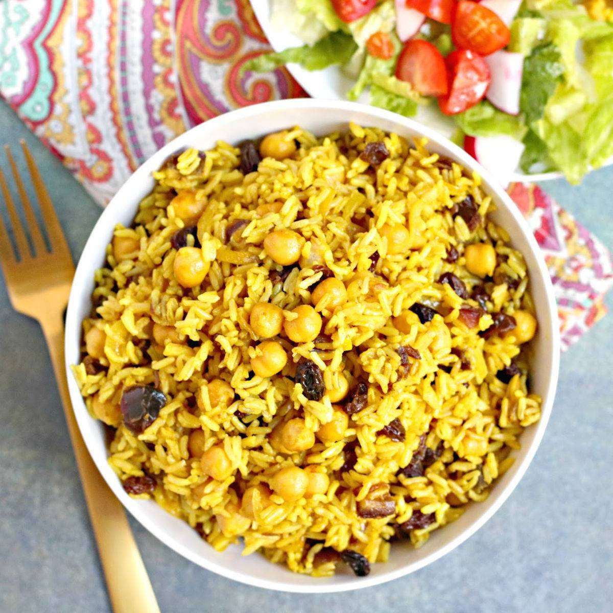 Bowl of basmati rice pilaf with chickpeas and dried fruit.