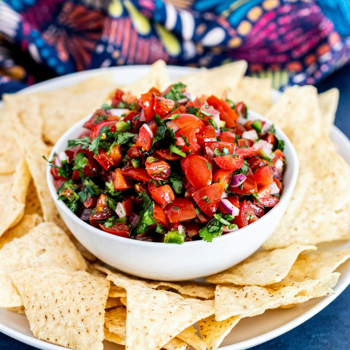 Bowl of cherry tomato salsa surrounded by tortilla chips.