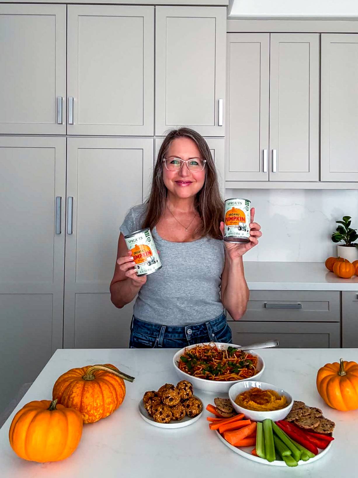Amy in her kitchen holding cans of pumpkin puree.