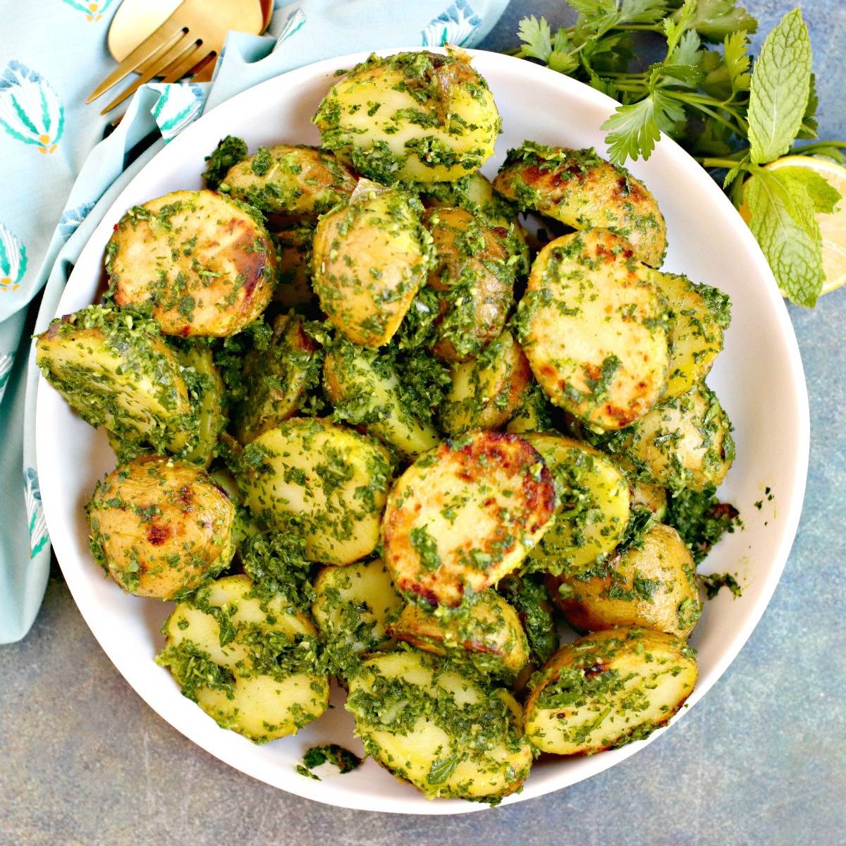 Bowl of grilled potatoes tossed with lemon herb sauce.