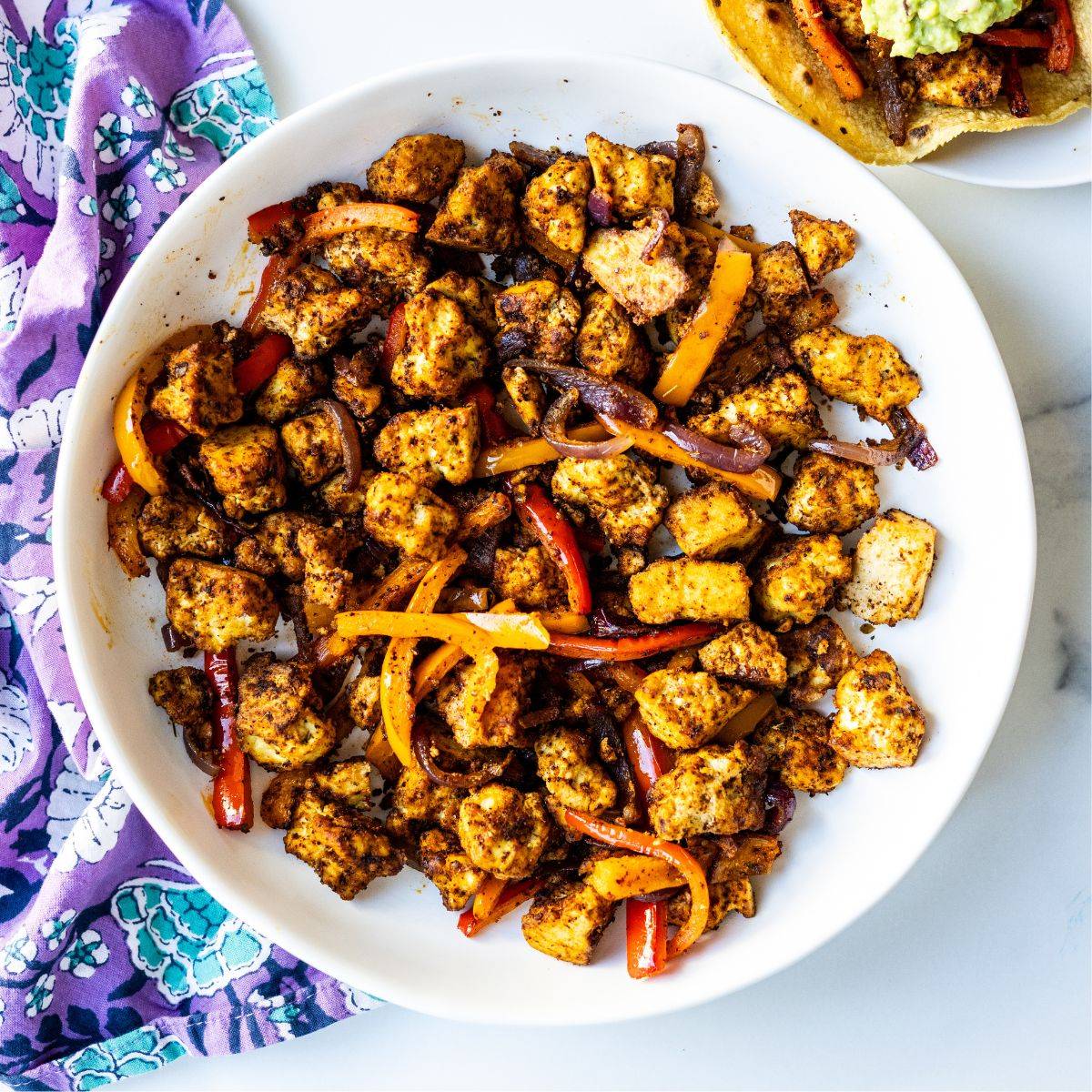 Plate of tofu fajitas with bell peppers and red onion.